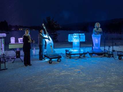Terje Isungset Quartet. 4 musicians stand in the ice of Norway at night, with  4 ice instruments lit up. An Ice double bass, iceophone, ice harp and ice percussion.