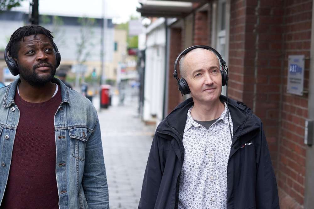 Reading Audio Trails. Aundre Goddard and Richard Bentley walking along the street with headphones on.