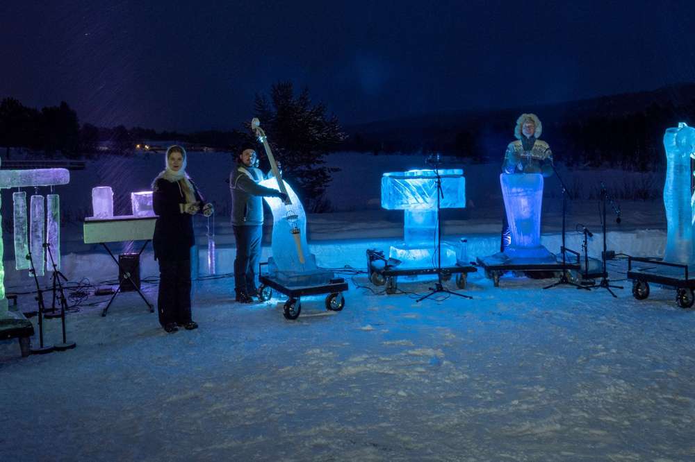 Terje Isungset Quartet. 4 musicians stand in the ice of Norway at night, with  4 ice instruments lit up. An Ice double bass, iceophone, ice harp and ice percussion.